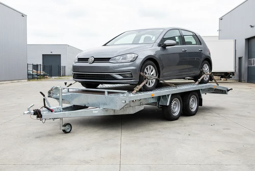 Porte-voiture à double essieu, une citadine grise sanglée sur le plateau